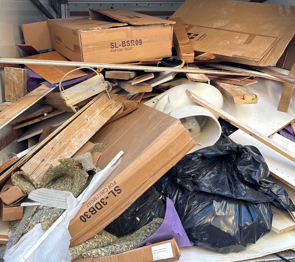 Renovation debris, wood and removed bathroom fixtures loaded for haul-away